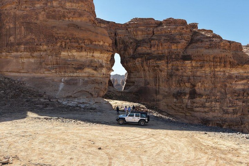 Un jeep sur un chemin de terre, avec une grande formation rocheuse en arrière-plan. 4