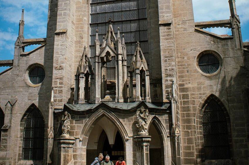 Una iglesia histórica con arcos apuntados, una torre central imponente y estatuas en la entrada. 2