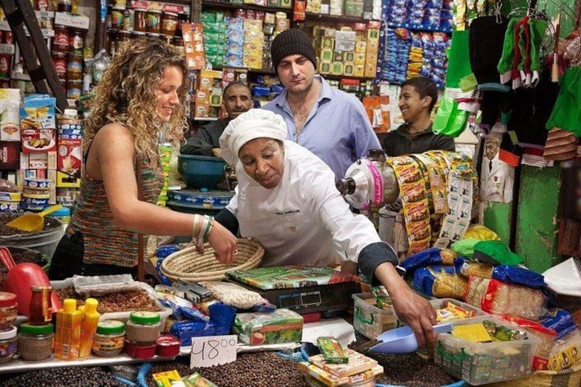 Une scène de marché où l’on voit des gens faire leurs courses, et une étiquette de prix indiquant 48,00. 2