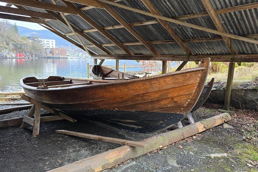 Een oude houten boot onder een overkapping aan een rustige rivier. 2