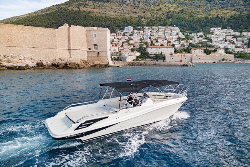 A white speedboat on water with a backdrop of a coastal town and a historic fort. 2