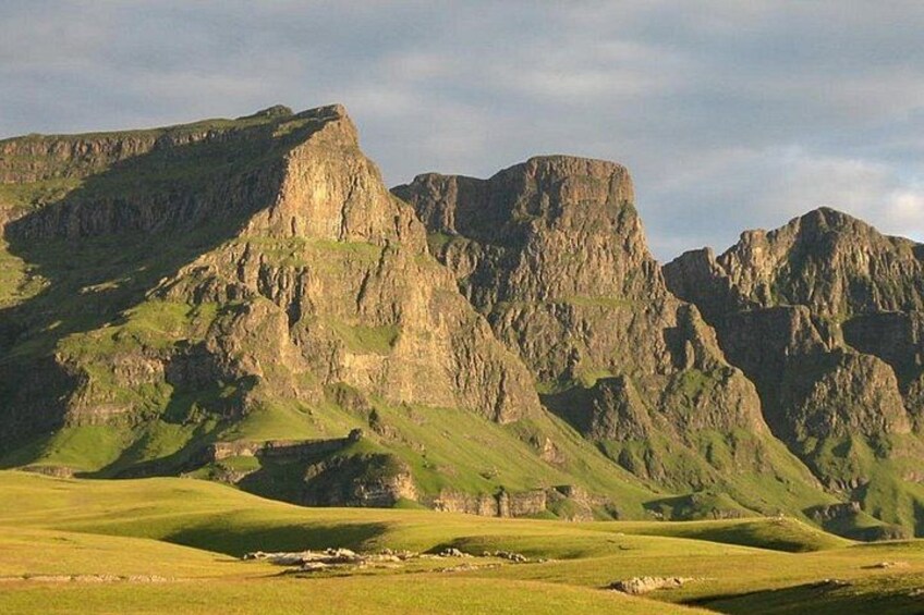 A mountainous landscape with green grassy valleys and rocky cliffs. 4