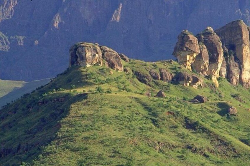 A green hill with rocky outcrops and a body of water in the background. 3
