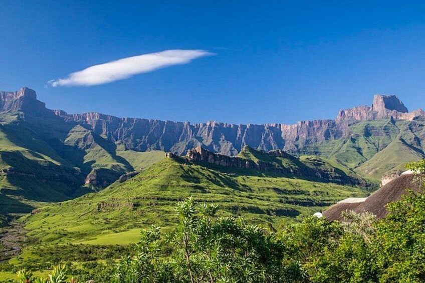 A mountainous landscape with green hills and rocky cliffs under a clear blue sky. 1