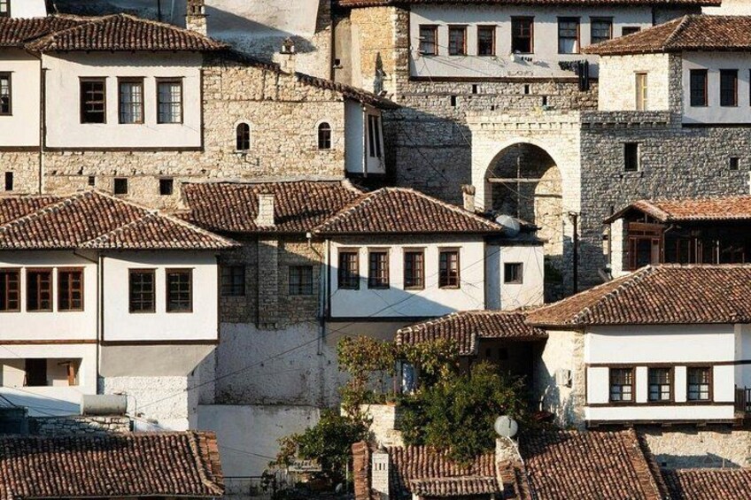 A historic town with stone buildings, terracotta roofs, and a prominent archway. 3