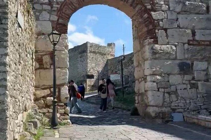 An ancient stone archway with tourists walking through it. 2
