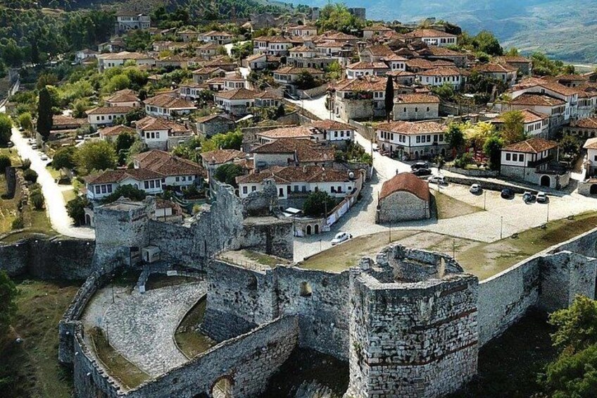 A historic town with a prominent stone castle, terraced houses, and a river. 5