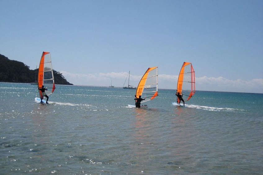 Drei Windsurfer auf ruhiger See unter strahlendem Himmel. 5