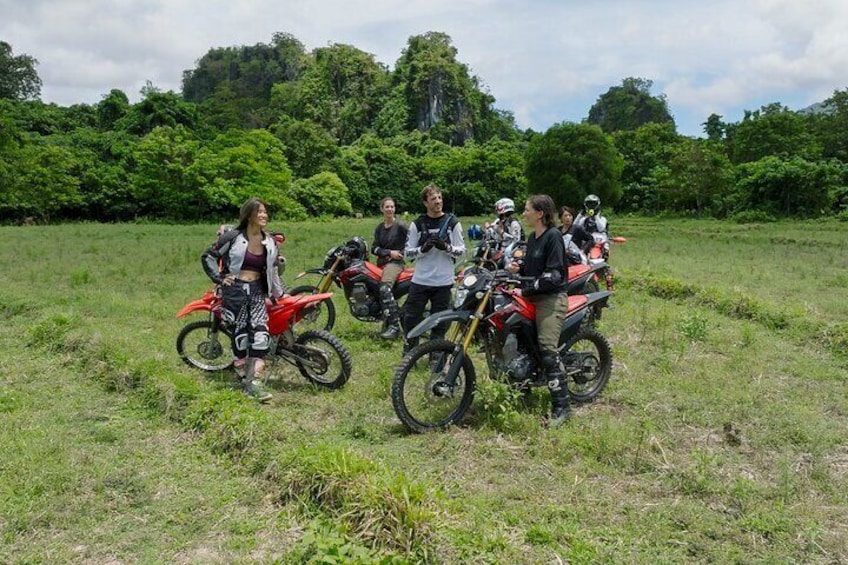 A group of people on motorcycles in a grassy field with trees in the background. 2