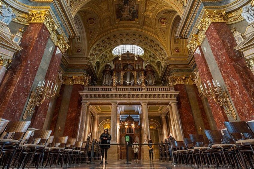 Een sierlijk interieur met marmeren zuilen, een statige trap en een groot orgel. 3