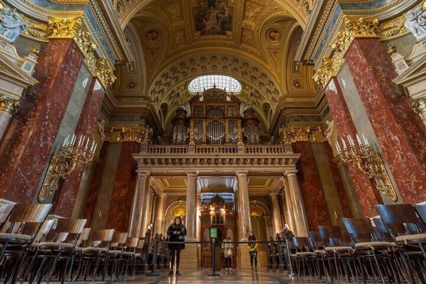 Een versierd kerkinterieur met marmeren zuilen, een groot orgel en een hoog plafond met ingewikkelde decoraties. 4