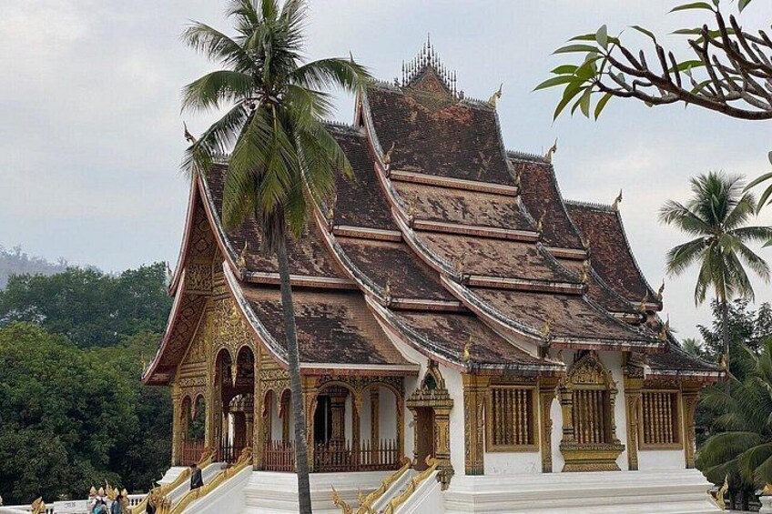 Et traditionelt thai tempel med detaljeret arkitektur, en trappe og palmer. 1