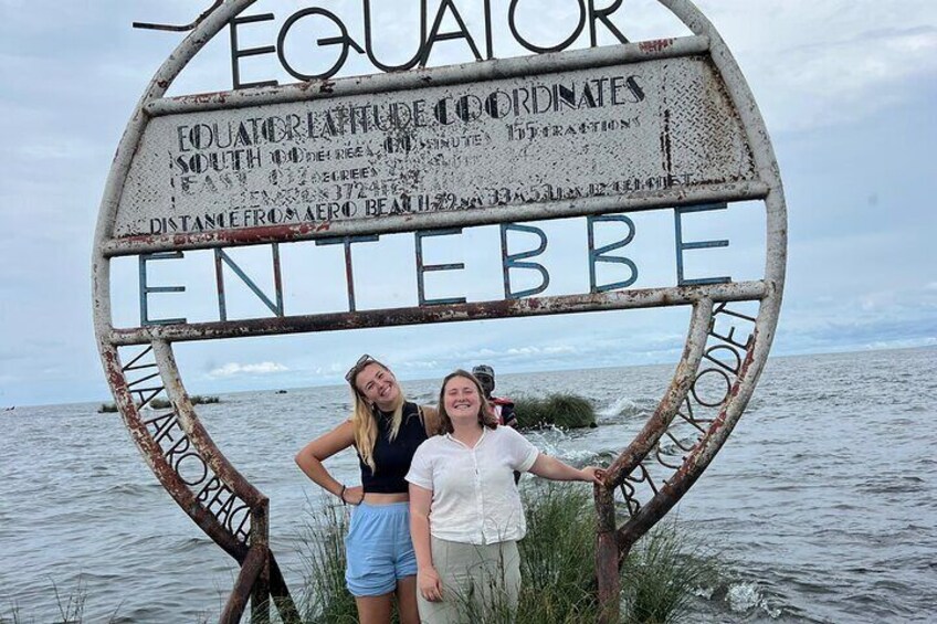Two people standing in front of a sign with 'Equator' and 'Equator Coordinates' written on it. 5