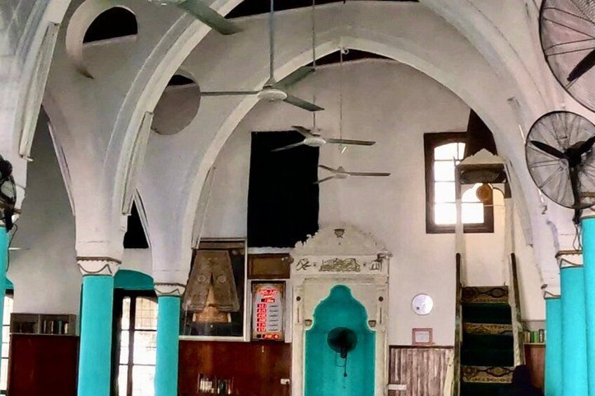 An interior with arched ceilings, a bell tower, and a fan. 2