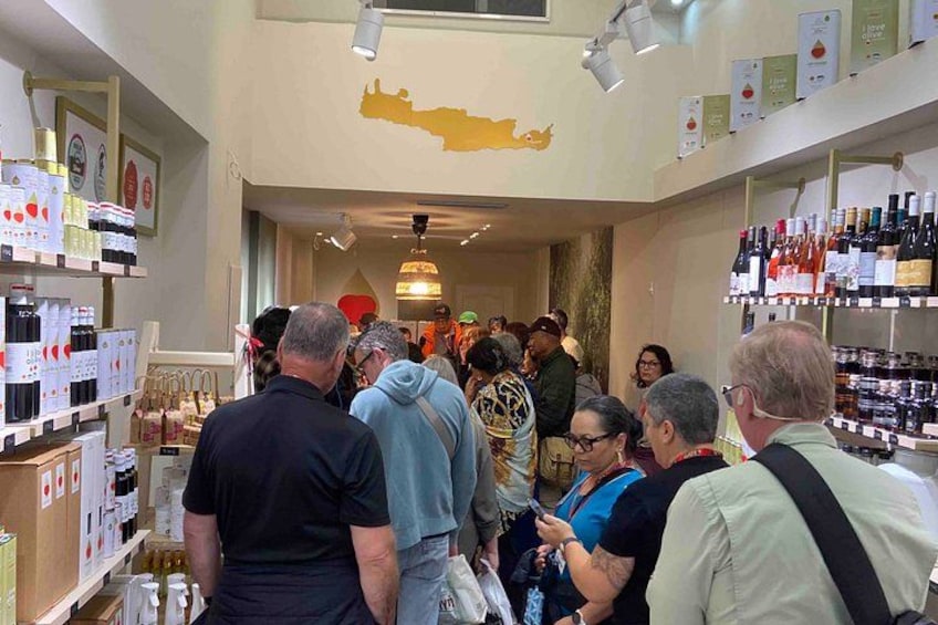 Una tienda de vinos interior llena de gente, con estanterías repletas de botellas y un mapa en la pared. 2