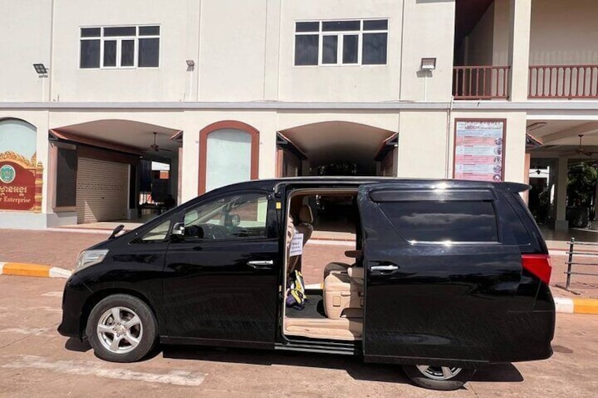 A black minivan parked in front of a building with multiple arches and a signboard. 3