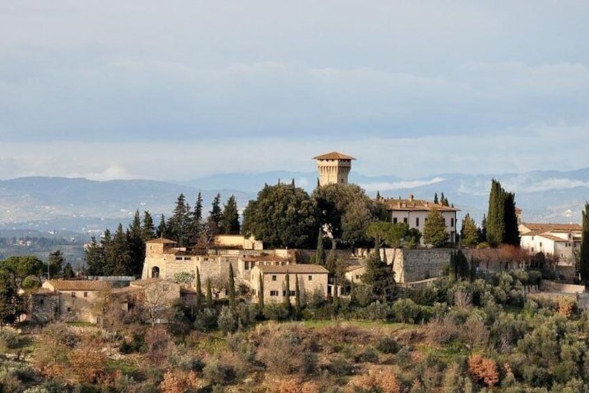Un pueblo histórico con edificios antiguos, una torre destacada y montañas al fondo. 5