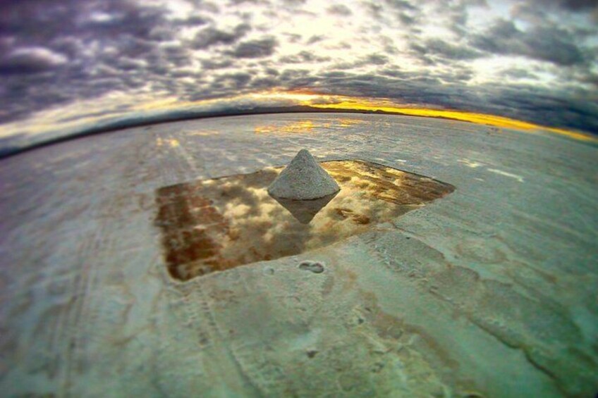 A concrete surface with a triangular object and a reflection of a cloudy sky. 2