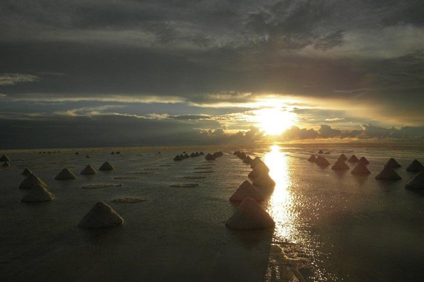 A beach with large rock formations and the sun setting in the background. 5