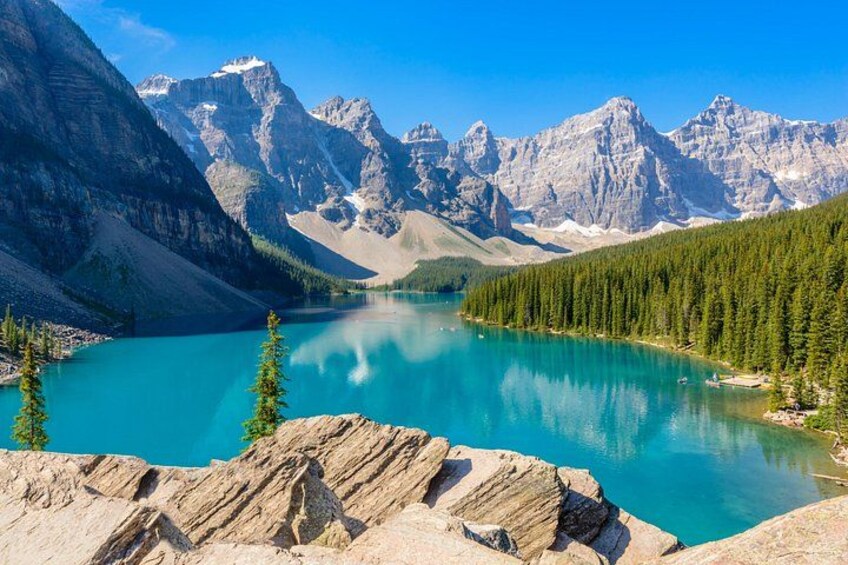 A turquoise lake surrounded by mountains and dense forest. 4