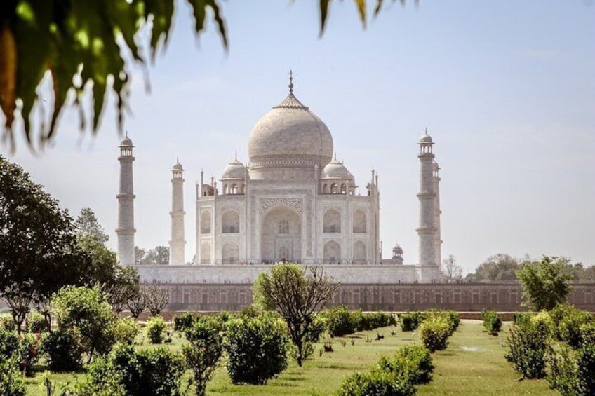 Taj Mahal med fire minareter og en stor central kuppel, omgivet af en velholdt have. 1