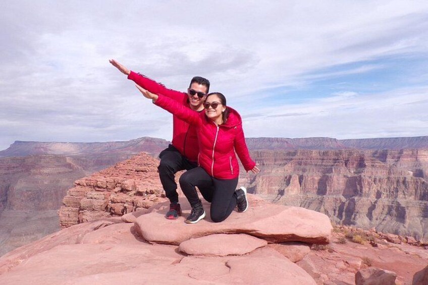 A couple posing on a rock formation with a canyon in the background. 2