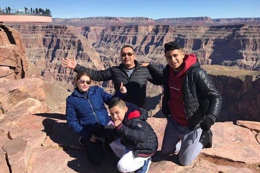 A group of people posing on a rocky outcrop with a canyon in the background. 5