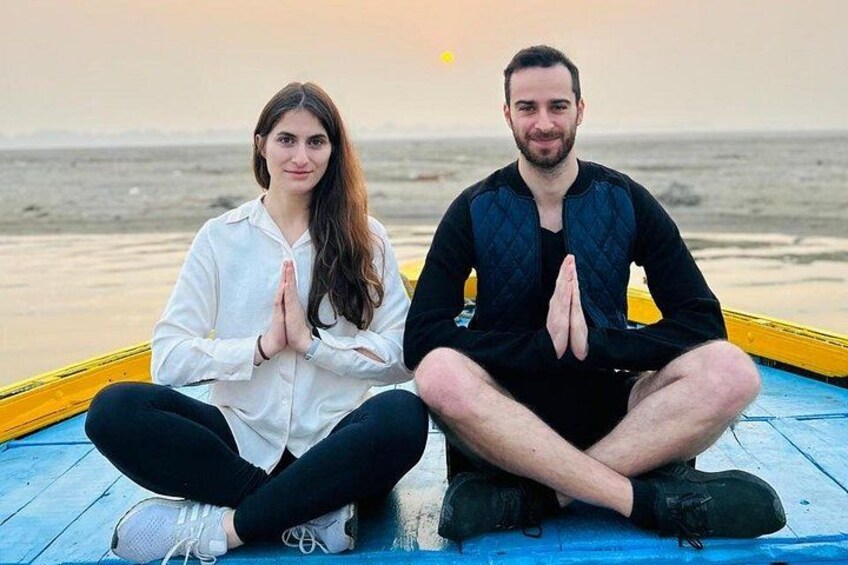 Dos personas sentadas en un bote en la playa, con el océano al fondo. 1