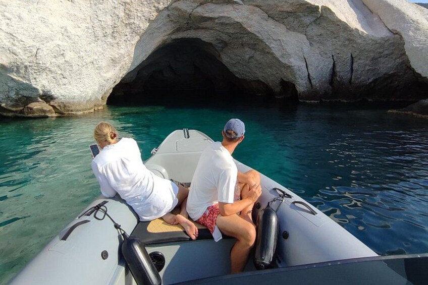 Twee personen op een boot nabij een rotsachtige kustlijn. 2