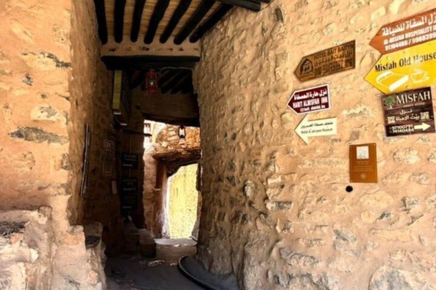 Un étroit passage bordé de murs en pierre et agrémenté de panneaux en arabe. 3