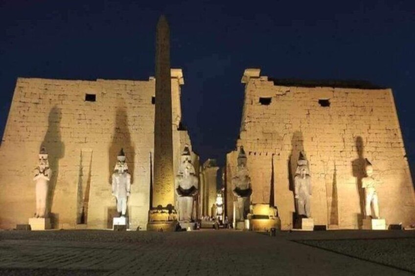 An ancient Egyptian temple at night with statues and an obelisk. 1