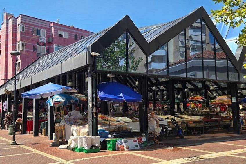 Een markt buiten met kramen en parasols. 5