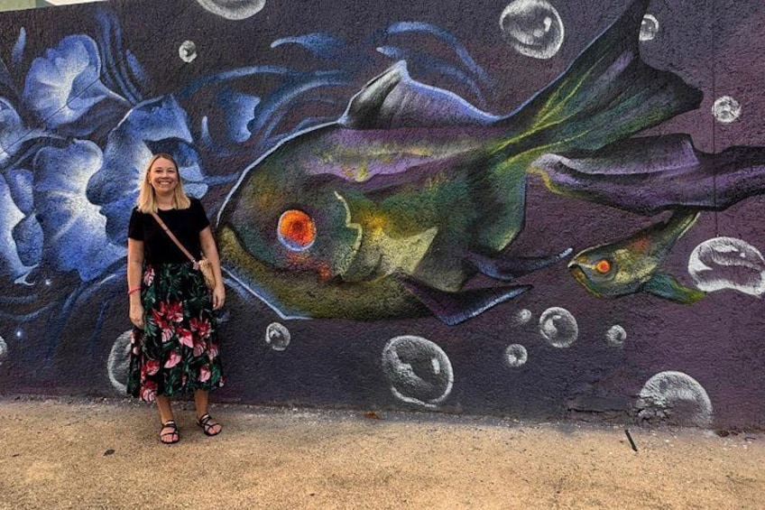 A person standing in front of a mural with fish and bubbles. 3