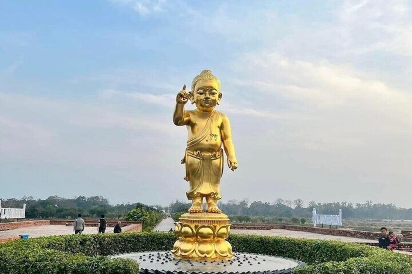 A large golden statue of a figure in a meditative pose, surrounded by a circular garden with a paved walkway. 1