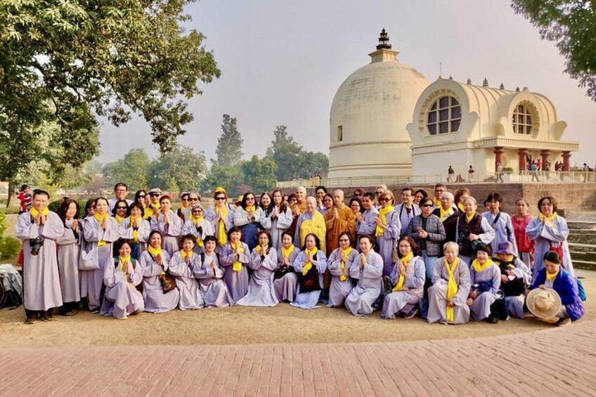 A group of people in traditional attire posing in front of a large white building with domes. 3