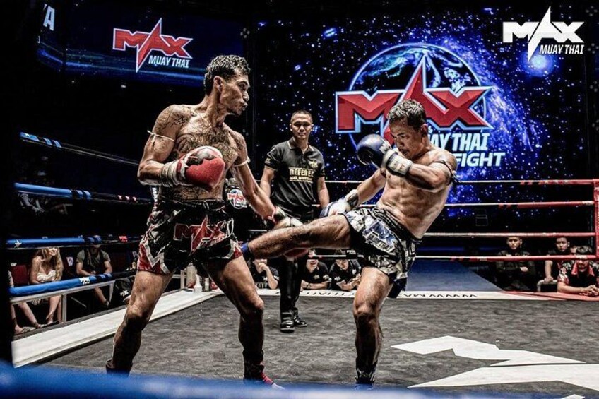 En boksekamp i en ring med et 'MAX Muay Thai Fight' logo i baggrunden. 5