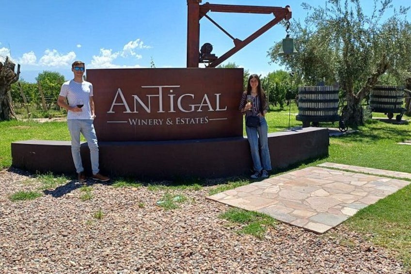 Señal de Antigal Winery & Estates con un camino de piedra y follaje al fondo. 4