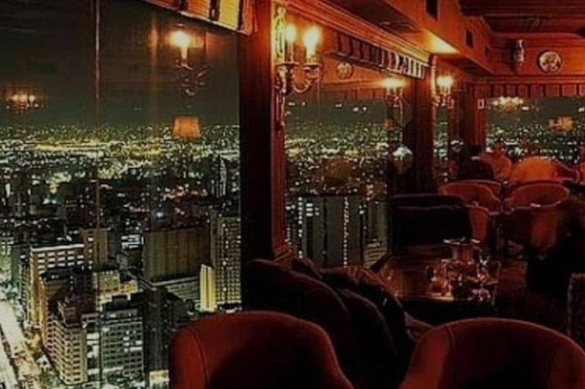 Un bar con vistas a la ciudad, mesas, sillas y un amplio ventanal. 3