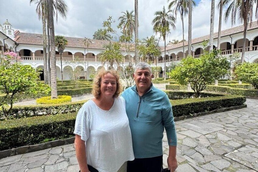 Un patio con palmeras, piso de baldosas y un edificio con arcos. 2