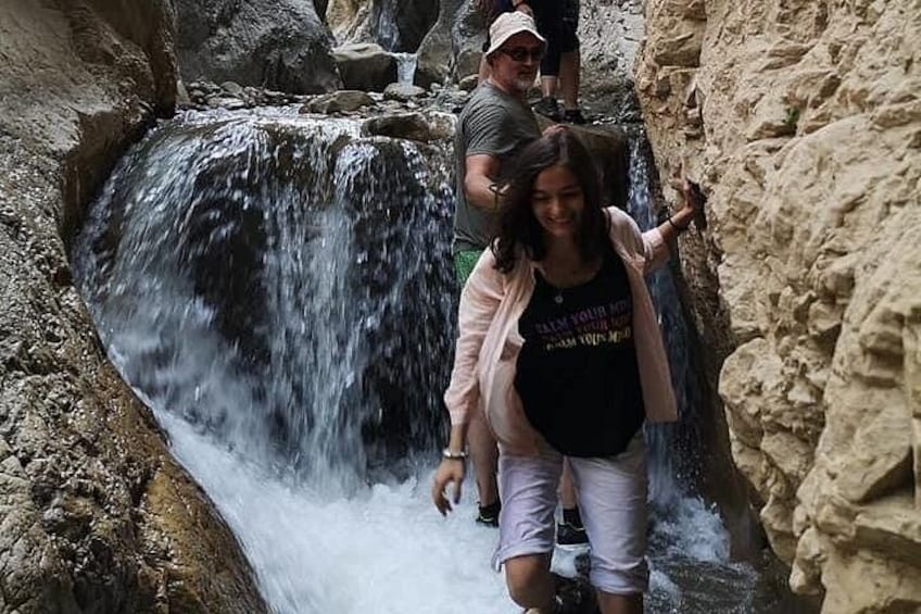 Una cascada en un terreno rocoso con gente caminando cerca. 2