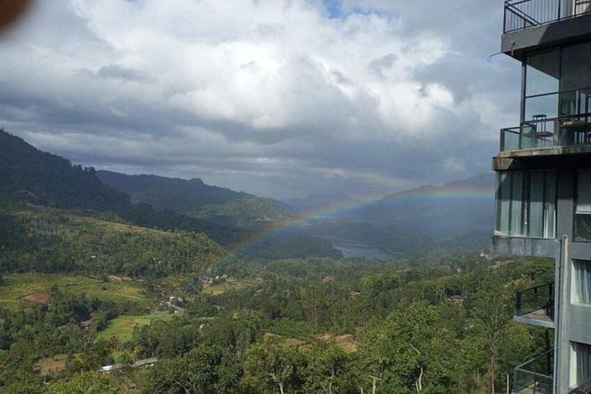 A mountainous landscape with a rainbow, a building, and a river. 1