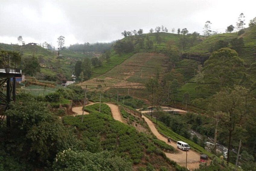 A hilly landscape with terraced fields, a dirt path, and a white vehicle. 5