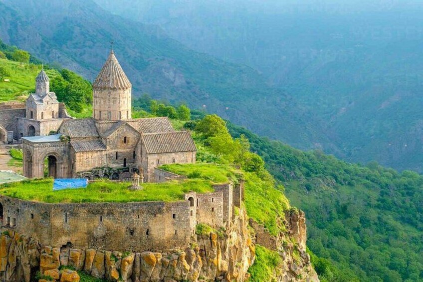 A historic church on a cliffside with a mountainous backdrop. 4