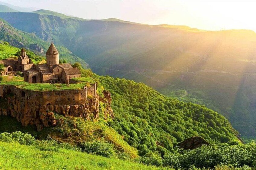 A historic building on a hillside with a dome, surrounded by lush green mountains. 3