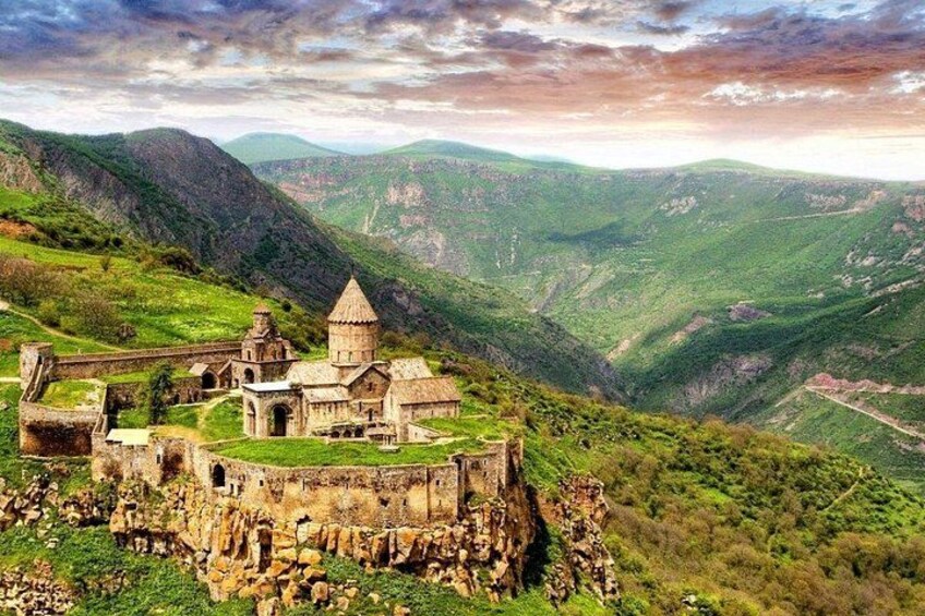 A historic stone church on a hilltop with surrounding lush green hills and valleys. 2