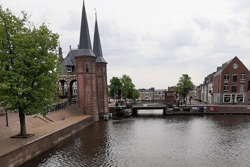 A canal with a bridge, a historic building with two spires, and a tree-lined walkway. 3