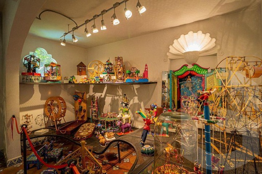 Ein Zimmer voller bunter Spielsachen und Dekorationen, darunter ein Riesenrad, eine Drehscheibe und eine große Glaskuppel. 4