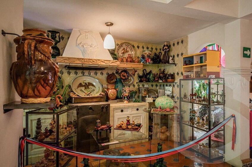 Ein Zimmer mit Regalen, die verschiedene Dekorationsgegenstände, eine große Vase und eine Vitrine mit Figuren zeigen. 2