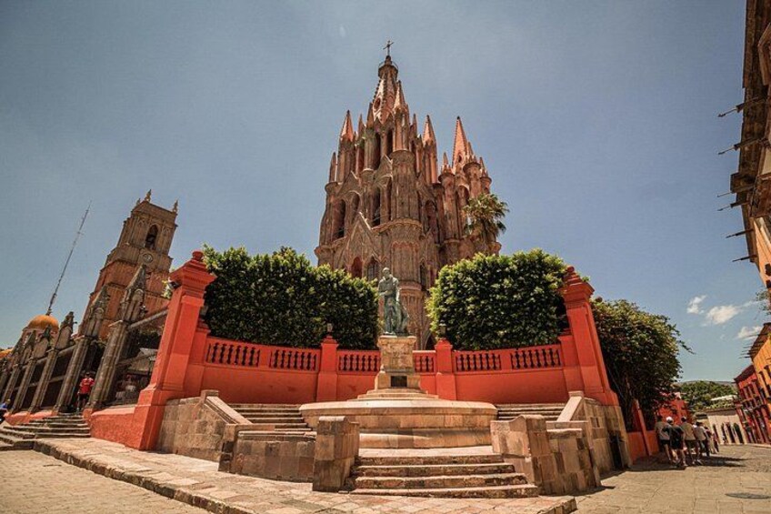 Ein Dom mit einem hohen Turm, eine Statue davor und eine rote Einfriedung. 1