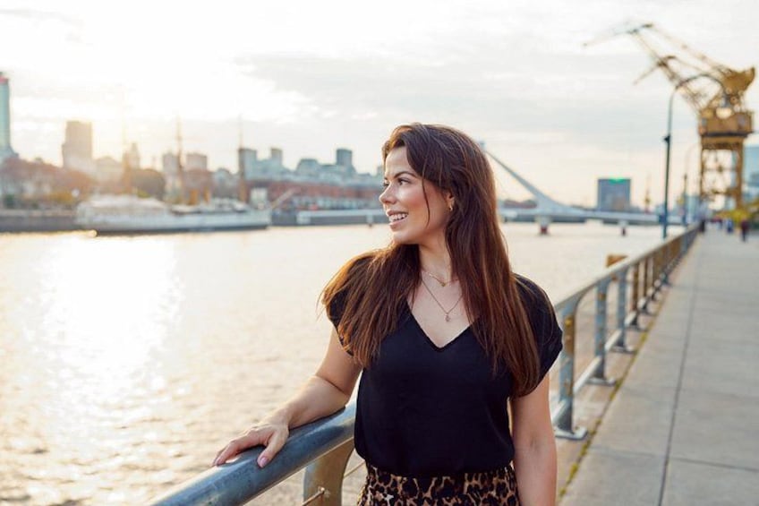 A person standing on a waterfront promenade with a city skyline in the background. 2